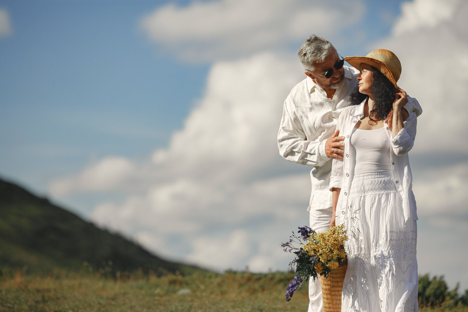 Mature couple standing on a grassy hillside with wildflowers